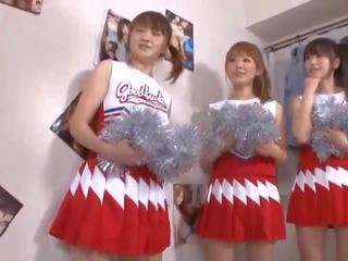 Kolme iso tiainen japanilainen cheerleaderit jakaminen putz